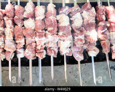 Diverse le materie infilzato shish kebab (shashlyk) da carne di maiale sul braciere a caldo con del carbone Foto Stock