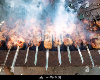 La cottura di shish kebab (shashlyk) da carne di maiale sul braciere all'aperto sulla soleggiata giornata estiva Foto Stock