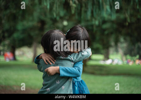 Bambina che abbraccia ogni altri amici Foto Stock