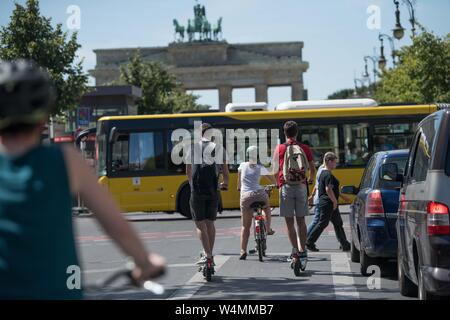 Berlino, Germania. Il 24 luglio, 2019. E-scooter, ciclisti, pedoni, gli automobilisti e un bus LPP soddisfare a un semaforo rosso davanti alla Porta di Brandeburgo. Credito: Jörg Carstensen/dpa/Alamy Live News Foto Stock