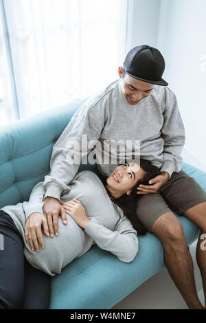 Una moglie incinta giace sul suo marito giro durante i momenti di relax Foto Stock