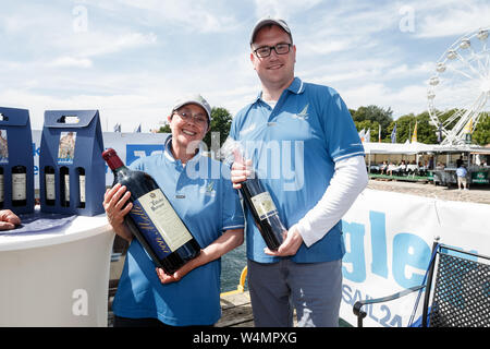 24 luglio 2019, Schleswig-Holstein, Travemünde: Monika Heinold (Bündnis 90/Die Grünen), dopo aver vinto la regata Rotspon con il suo trofeo vincendo, 6 bottiglia da un litro di Lübecker Rotspon, sorge accanto al concorrente sconfitto e campione in carica Jan Lindenau (SPD), Sindaco di Lubecca. Foto: Markus Scholz/dpa Foto Stock