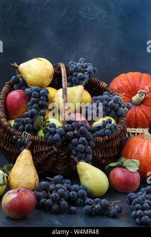 Autunno still life con mele, uva, la zucca e le pere situato su uno sfondo scuro, raccolto autunnale, mele, pere e uva nel cestello, spazio di copia Foto Stock