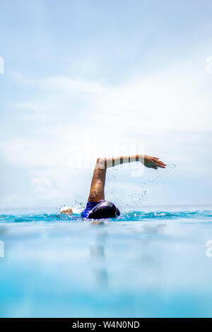 La donna non identificato anteriore facendo strisciare il nuoto nella piscina in vacanza. Foto Stock