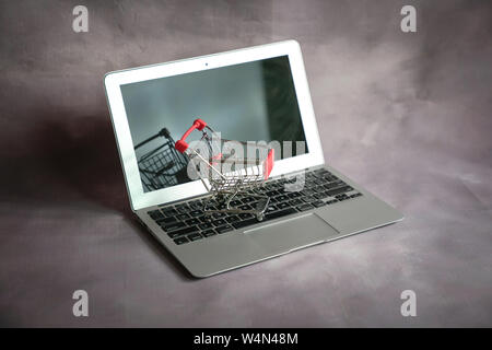 Mini carrello su un laptop. Shopping online o il concetto di ecommerce. Foto Stock