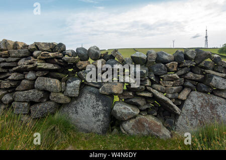 Un mal costruita in pietra a secco parete realizzata con grandi massi con fori in essa, nello Yorkshire, Regno Unito Foto Stock
