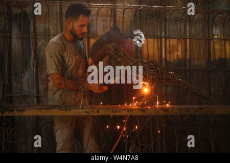 (190724) -- GAZA, luglio 24, 2019 (Xinhua) -- palestinese Hilles Anas rende un pezzo di arte con il ferro presso la sua officina di Gaza City, 24 luglio 2019. Anas Hilles, 27, ha lavorato come un fabbro per dieci anni. Egli crea bellissimi manufatti e scultura con ferro. (Foto di Khaled Omar/Xinhua) Foto Stock