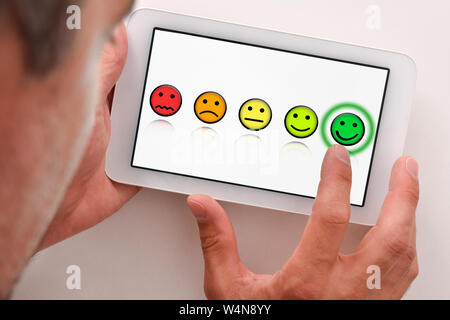 Uomo che forniscono una valutazione positiva su un dispositivo elettronico. Composizione orizzontale. Vista dall'alto. Foto Stock