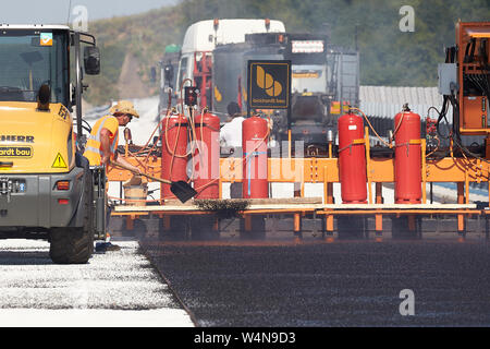 24 luglio 2019, Renania-Palatinato, Zeltingen-Rachtig: i lavoratori di asfaltatura della superficie stradale del ponte Hochmosel in costruzione a temperature molto al di sopra di 30 gradi Celsius. Non vi è alcun luogo ombroso su 160 metri di un edificio alto sopra la valle di Mosel. Foto: Thomas Frey/dpa Foto Stock