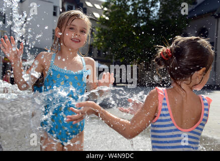 24 luglio 2019, Renania-Palatinato, Völklingen: Nele (l) e Mathilda rinfrescarsi in una fontana di acqua il gorgogliamento di una parete nella zona pedonale. Oggi Völklingen è uno dei punti più caldi in Germania. Foto: Harald Tittel/dpa Foto Stock