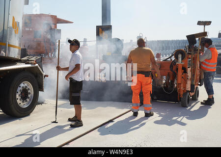 24 luglio 2019, Renania-Palatinato, Zeltingen-Rachtig: i lavoratori di asfaltatura della superficie stradale del ponte Hochmosel in costruzione a temperature molto al di sopra di 30 gradi Celsius. Non vi è alcun luogo ombroso su 160 metri di un edificio alto sopra la valle di Mosel. Foto: Thomas Frey/dpa Foto Stock