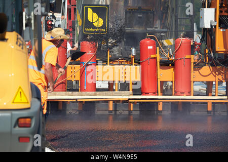 24 luglio 2019, Renania-Palatinato, Zeltingen-Rachtig: i lavoratori di asfaltatura della superficie stradale del ponte Hochmosel in costruzione a temperature molto al di sopra di 30 gradi Celsius. Non vi è alcun luogo ombroso su 160 metri di un edificio alto sopra la valle di Mosel. Foto: Thomas Frey/dpa Foto Stock