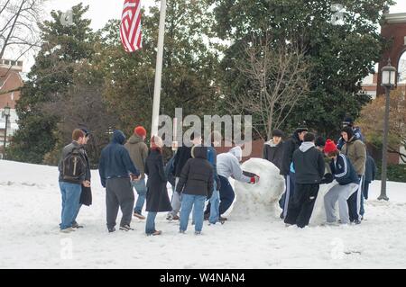 Un gruppo di studenti al di fuori su di un inverno di giorno, guardare i colleghi costruire un pupazzo di neve su un quad vicino al Homewood Museum, presso la Johns Hopkins University, Baltimora, Maryland, 14 febbraio 2007. Dall'Homewood raccolta di fotografie. () Foto Stock