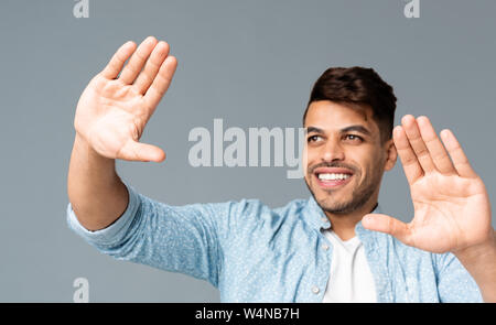 Sorridente Guy rendendo il telaio a mano qualcosa di visualizzazione Foto Stock