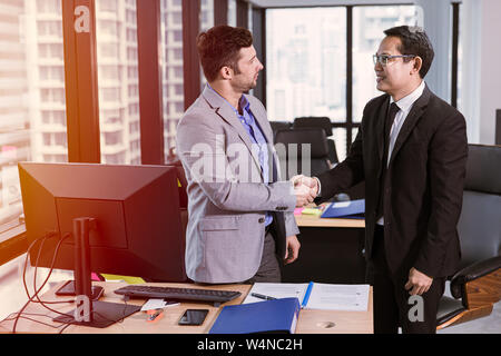 Imprenditore mix gara soddisfare sorridente e agitare le mani insieme in ufficio Foto Stock