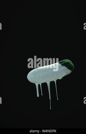 Verde di gocciolamento di cetriolo vernice bianca su un nero blackground. Foto Stock