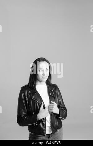 Ritratto in studio di un attraente giovane donna in una t-shirt bianco e nero giacca di pelle contro uno sfondo semplice Foto Stock