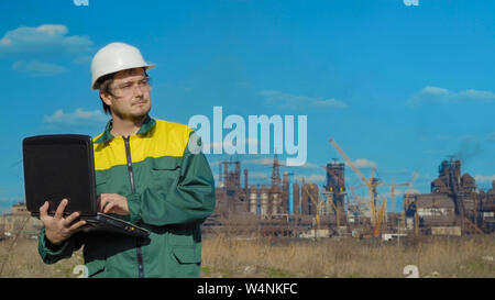 Il maschio di progetti tecnici i lavori. Giornata di sole e nuvole. L'uomo è vestito in un verde giubbotto di occhiali da sole Foto Stock