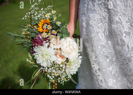Sposa è in possesso di un mazzo di fiori di primavera fresca e fiori estivi in colori pastello su uno sfondo sfocato, il fuoco selettivo Foto Stock
