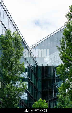 Kemper Platz, Berlin, Germania - Luglio 07, 2019: una moderna facciata in vetro e di un edificio vicino al Sony Center in contrasto con il verde degli alberi in foregro Foto Stock