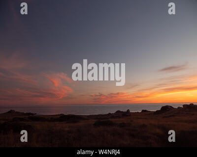 Tramonto sulla scogliera costiera con l'oceano a distanza Foto Stock