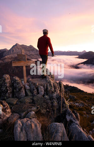 L'uomo osservare nebbie all'alba dalla cima di alcune montagne Foto Stock