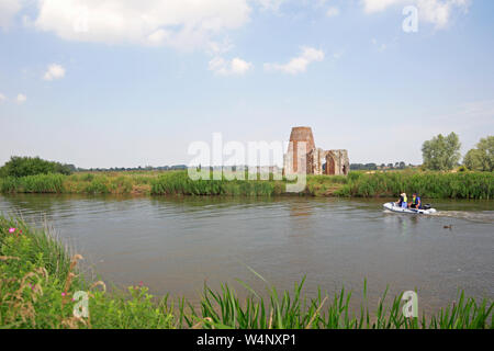 Due persone in un gommone passando St Benet le rovine dell'Abbazia sul fiume Bure a South Walsham, Norfolk, Inghilterra, Regno Unito, Europa. Foto Stock