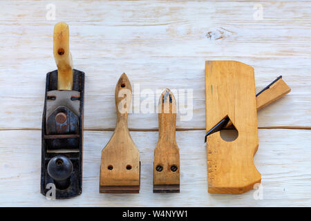 Falegnameria di vecchi attrezzi di mano, ruspe e cicli giacciono su un bianco tavolo di legno. Foto Stock