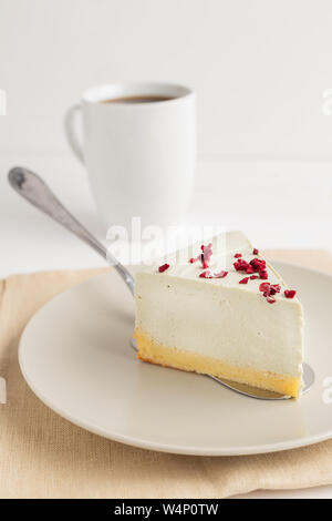 Fetta di matcha cheesecake con secchi berry sulla parte superiore e bianco coppa piena di caffè su sfondo bianco Foto Stock