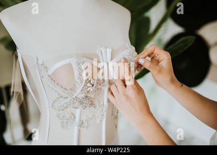 Close up di mani cucito un abito da sposa Foto Stock