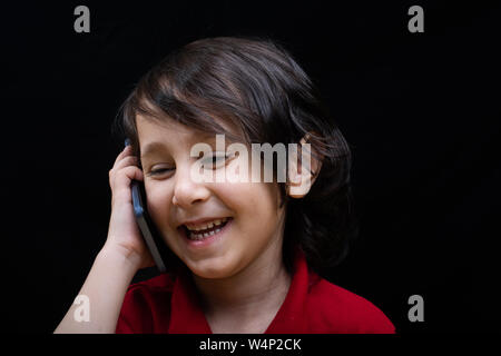 Little Boy tenere lo smartphone come moderna comunicazione mobile gadget Foto Stock