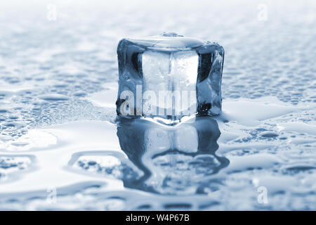Una singola fusione cubo di ghiaccio con le tonalità blu Foto Stock