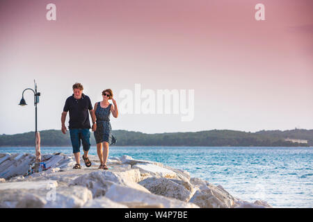 Croazia, Istria, giovane godersi il tramonto sul molo Foto Stock