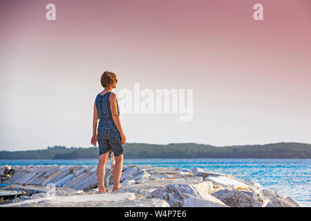 Croazia, Istria, giovane godersi il tramonto sul molo Foto Stock