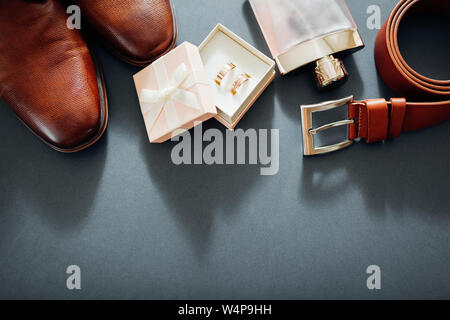 Lo sposo il giorno delle nozze accessori. Brown scarpe di cuoio, cinghia, profumo, anelli d oro nella casella n. Moda maschile Foto Stock