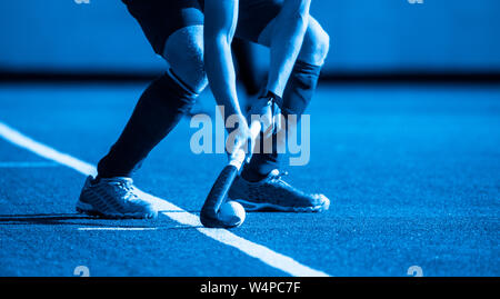 Campo di hockey player,pronta per passare la palla a un compagno di squadra filtro blu. Foto Stock