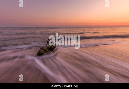 Bellissimo colpo di oceano e un driftwood al tramonto.lunga esposizione con spazio di copia Foto Stock