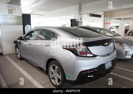 Chevrolet Volt veicolo elettrico collegato alla presa di corrente e la carica a un veicolo elettrico stazione di carica a San Ramon, in California, con accesso California Okay aria pulita veicoli sticker visibile, Settembre 26, 2018. () Foto Stock