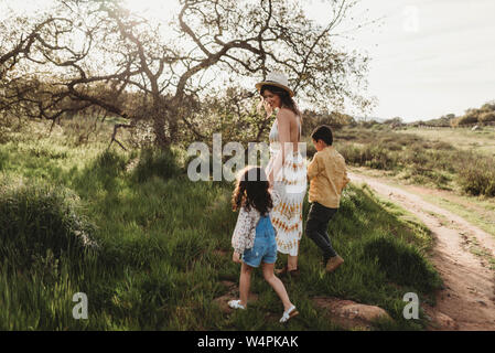 Vista laterale della madre e bambini a piedi in campo insieme Foto Stock