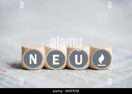 A cubetti con la parola "nuovo" (in tedesco) su un giornale Foto Stock
