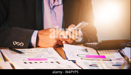 Imprenditori conte di Denaro e finanze del piano per la realizzazione di progetti e di utilizzare calcolatrici per l'analisi dei documenti di progetto grafico e lo schema finanziario lavorando in b Foto Stock