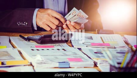 Imprenditori conte di Denaro e finanze del piano per la realizzazione di progetti e di utilizzare calcolatrici per l'analisi dei documenti di progetto grafico e lo schema finanziario lavorando in b Foto Stock