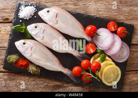 Orata bram di mare Pesce con ingredienti di close-up su una scheda di ardesia sul tavolo. parte superiore orizzontale vista da sopra Foto Stock