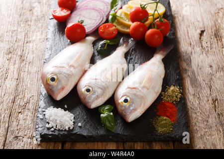 Materie rosa pesce dorado con ingredienti di close-up su una scheda di ardesia sul tavolo orizzontale. Foto Stock