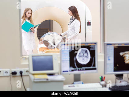 Macchina MRI e schermate con medico e infermiere Foto Stock
