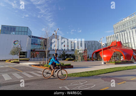 Ciclista maschio nella parte anteriore del nuovo campus della Emily Carr Università di Arte e Design sul Grande Nord in Vancouver, BC, Canada Foto Stock