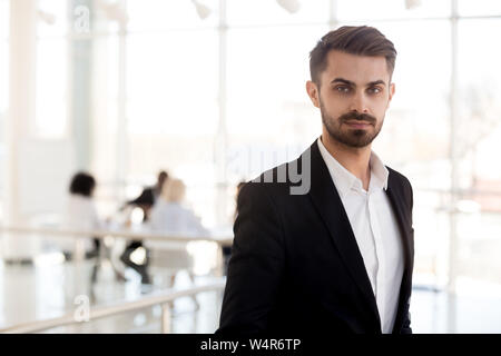 Colpo alla testa ritratto imprenditore fiducioso in tuta in posa di corridoio Foto Stock