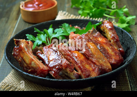 Antipasto di arrosto di maiale affettato nervature nella padella sul tavolo di legno, close up Foto Stock