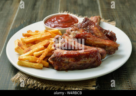 A FETTE fritte costolette di maiale, la salsa di pomodoro e patate fritte su piastra bianca, close up Foto Stock