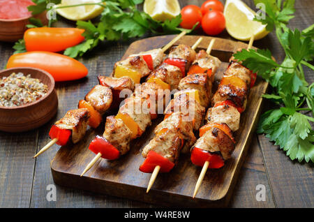Grigliata di spiedini di pollo con verdure sul tavolo di legno Foto Stock